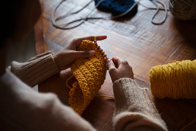 Free photo high angle young adult crocheting indoors