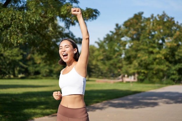 Free photo hooray victory smiling asian girl triumphing celebrating achievement running till finish shouting fr