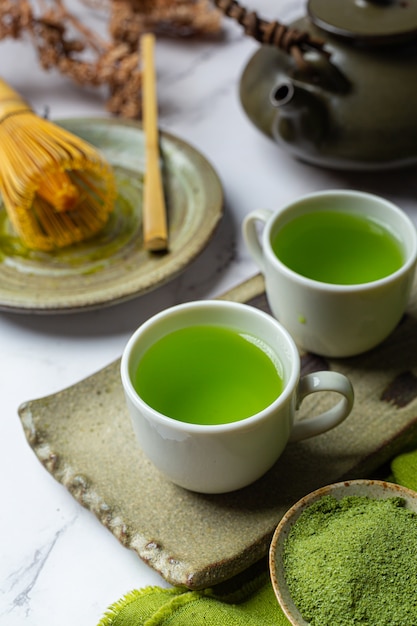 Free photo hot green tea in a glass with cream topped with green tea, decorated with green tea powder.