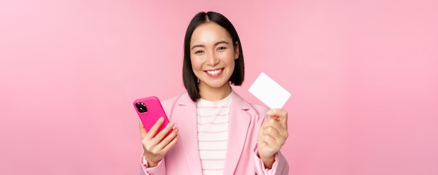 Free Photo image of smiling happy asian businesswoman showing credit card paying online on smartphone applicati