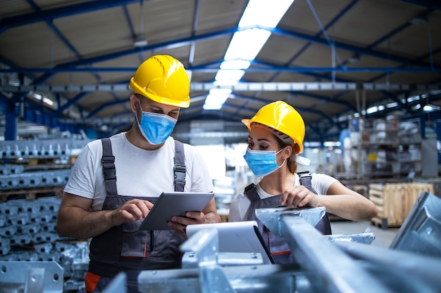 Free Photo industrial workers with face masks protected against corona virus discussing about production in factory