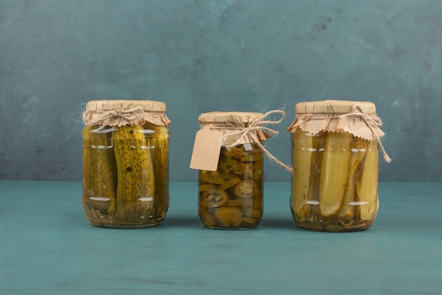 Free Photo jars of pickled cucumbers and jalapenos on blue table.