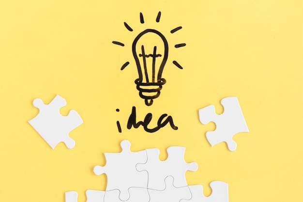 Free photo jigsaw puzzle and light bulb with idea word on yellow background