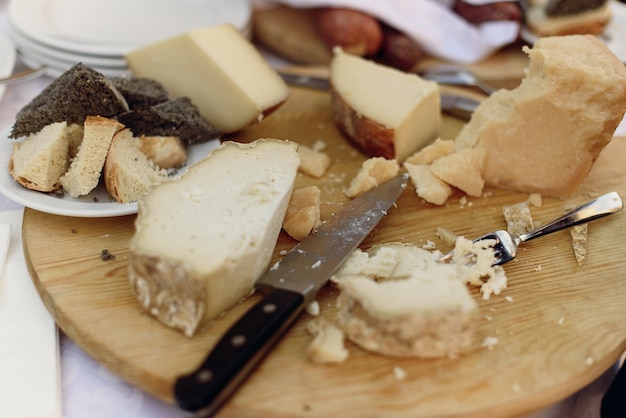 Free photo knife and fork lie on wooden plate with different kinds of chees