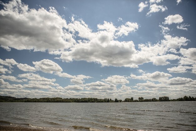 Foto gratuita un lago sotto il cielo nuvoloso con una foresta