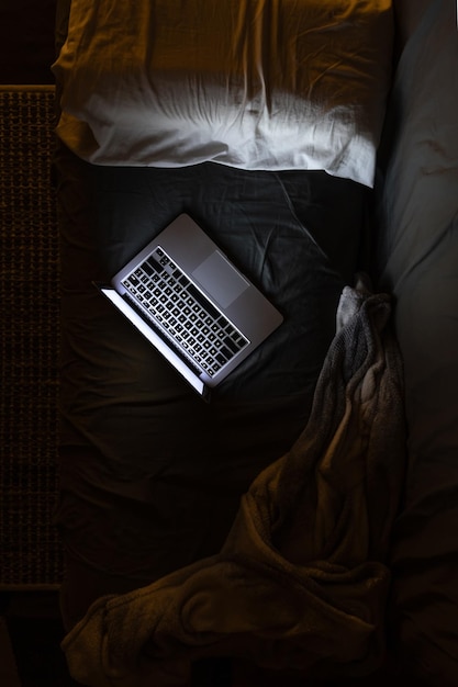 Laptop on the bed at night light from the laptop screen top view