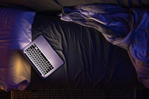 Laptop on the bed at night light from the laptop screen top view