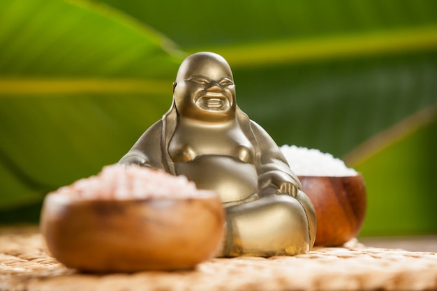 Free Photo laughing buddha figurine and sea salt in wooden bowl