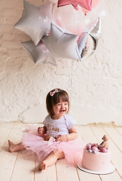 Free photo little birthday girl. charming baby in pink dress sits on the chair