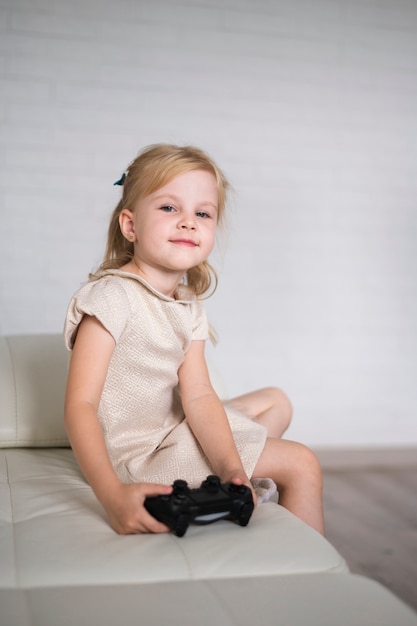 Free photo little girl sitting on couch with joystick