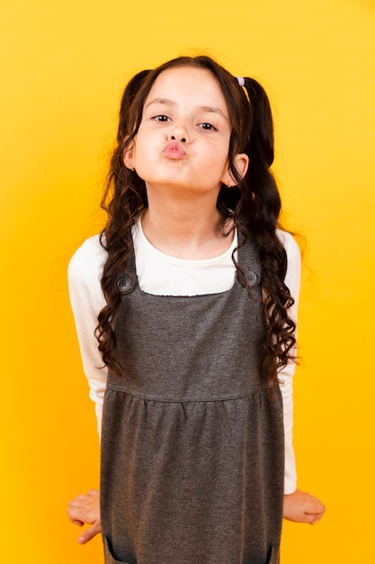 Free photo little girl with dress doing kiss pose