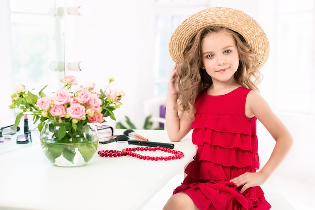 Free photo a little girl with red dress and cosmetics.