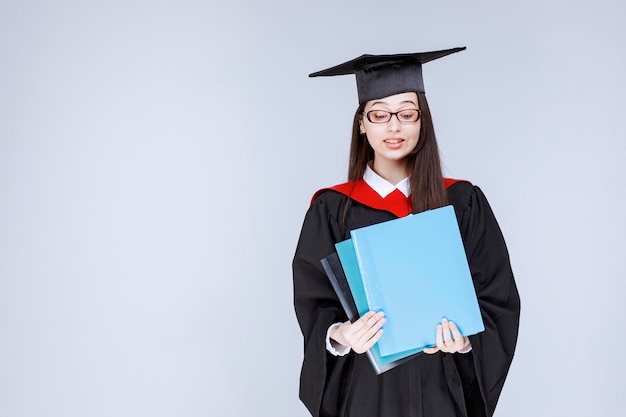 Long haired student in glasses folders in her hand standing. High quality photo