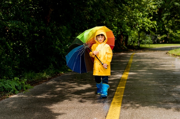 Free Photo long shot little boy holding an umbrella above his head