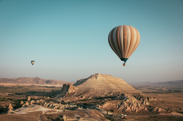 Free Photo long shot of multi-colored hot air balloons floating above the mountains