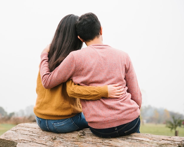 Free photo loving couple sitting on log and hugging