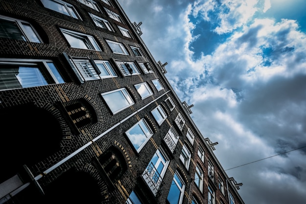 Low angle shot of a brick building with windows and a cloudy sky