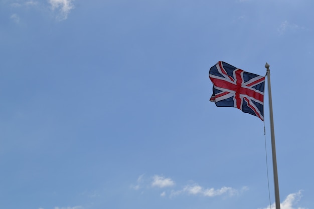 Free photo low angle shot of the flag of great britain on a pole under the cloudy sky