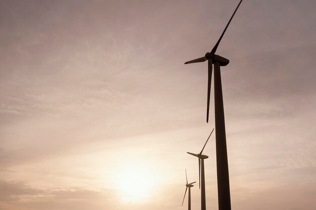 Free photo low angle of wind turbines at sunset generating energy