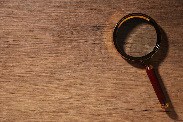 Free photo a magnifying glass in a black frame on a wooden background