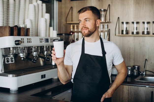 Free photo male barista holding coffee in cardboard cup