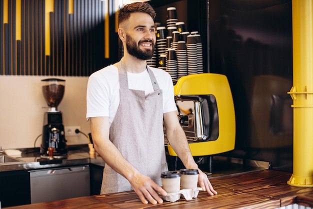 Free photo male barista serving coffee in cardboard cups