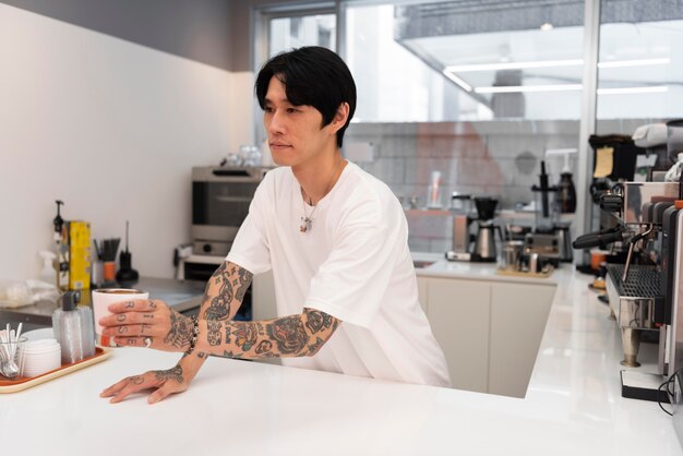 Male barista with tattoos serving coffee at the counter