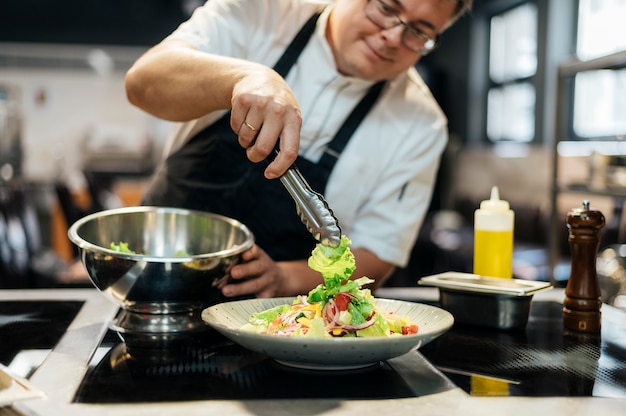 Foto gratuita cuoco unico maschio che mette insalata sulla zolla