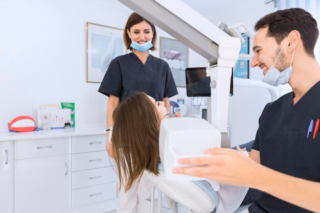 Male dentist scanning female patient's teeth with x-ray machine