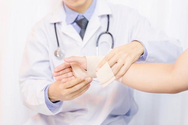 Free photo male doctor putting gauze on young man's hand in clinic, closeup. first aid