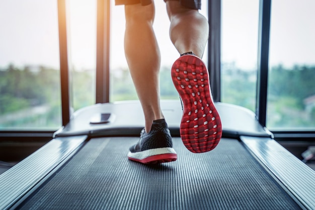 Male feet in sneakers running on the treadmill at the gym. Exercise concept.