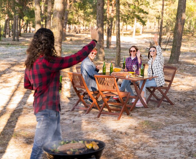 Man cheering with friends while holding beer and having a barbecue