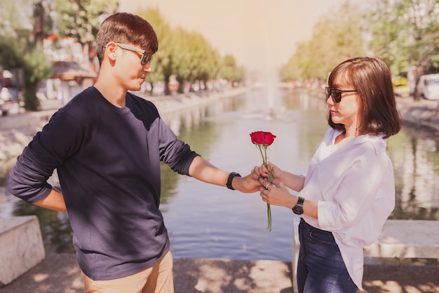 Free photo man handing a rose to a woman