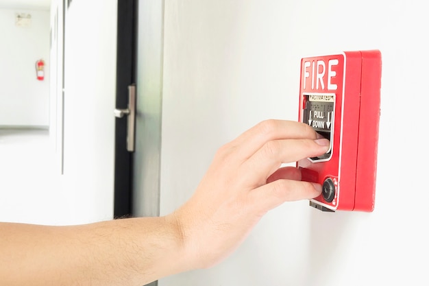 Free Photo man is reaching his hand to push fire alarm hand station