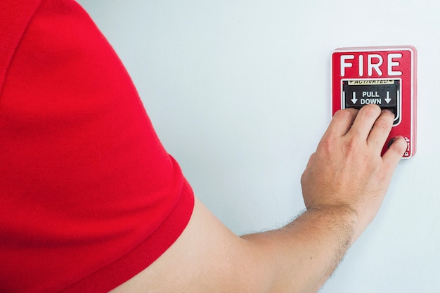 Free Photo man is reaching his hand to push fire alarm hand station