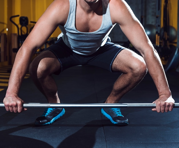 Free photo man lifting barbell in fitness club