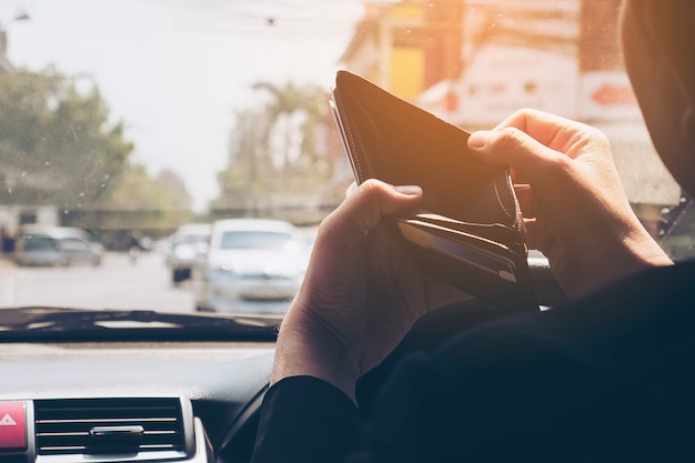 Free Photo man look at his empty wallet while driving car, dangerous behavior