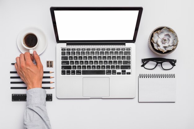 Man's hand holding coffee cup on office desk with arranged office supplies