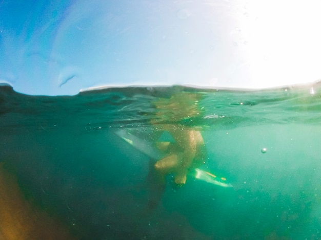 Free photo man sitting on surfboard in sea