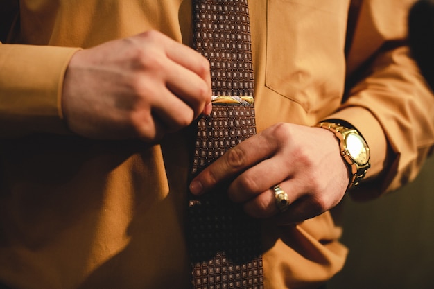 Free photo man with a gold watch adjusts a tie