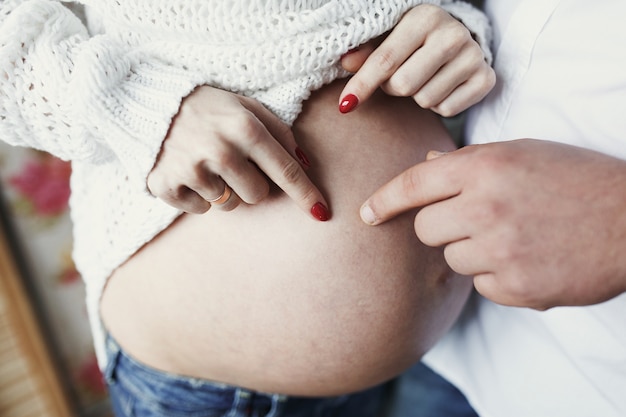 Free photo man and woman with red nails touch with their fingers her pregnant belly