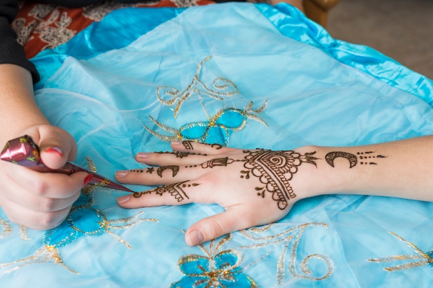 Free Photo master tattooing mehndi draws on lady hand