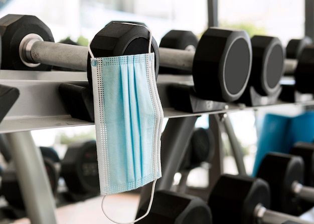 Medical mask in the gym hanging from weights