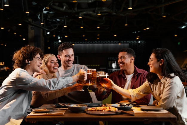 Free photo medium shot happy friends with beer mugs