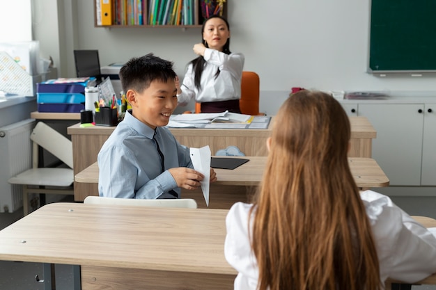 Foto gratuita ragazzo di tiro medio con aeroplanino di carta a scuola