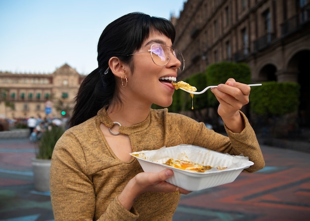 Free photo medium shot mexican woman eating ranchero food