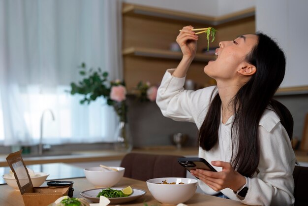 Free photo medium shot woman eating asian food