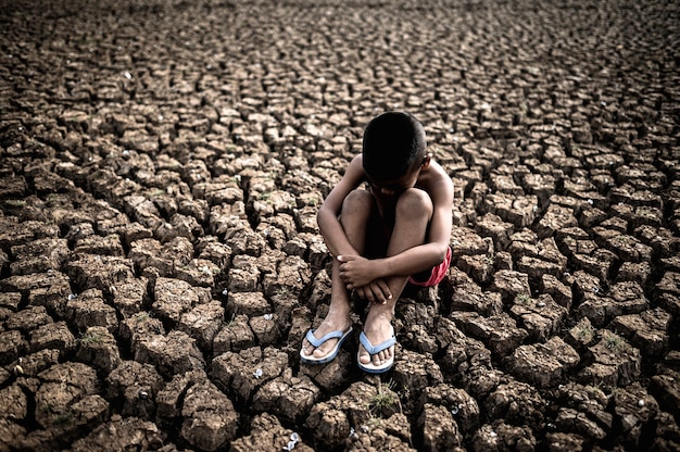 Men sitting hugging their knees, bent, bent on the dry soil, global warming