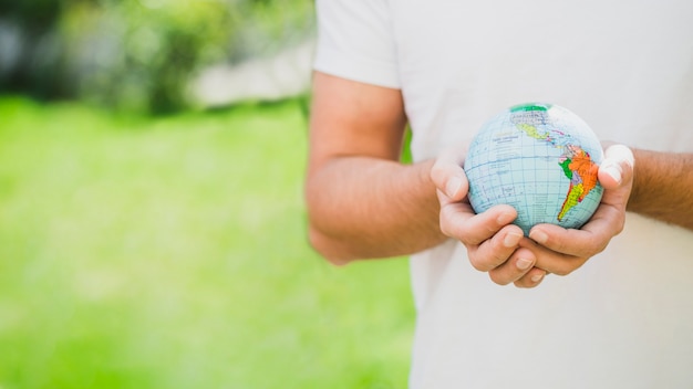 Free photo mid section of man holding globe in hand