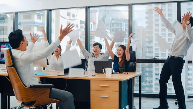 Free Photo millennial group of young businesspeople asia businessman and businesswoman throwing documents feeling happy of achievements after succeed result at meeting room at small modern office in urban city.